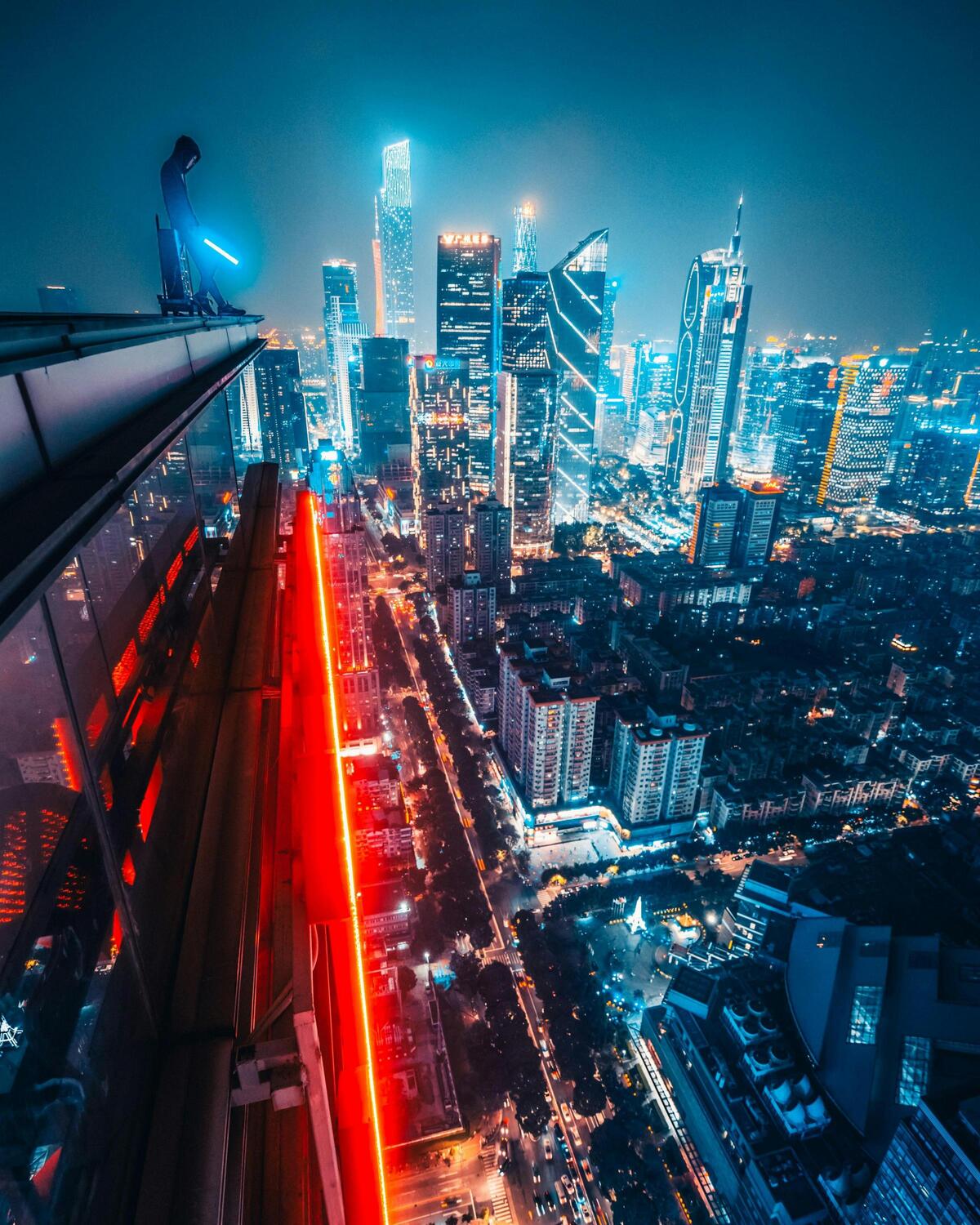 Hombre mirando la ciudad de noche con un sable de luz en la mano.